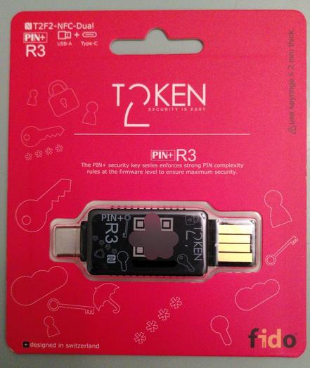 The packaging of the Token2 PIN+ Dual R3 is red and decorated with a couple security icons as illustrations in the background. Under see-through plastic resides the security key with a USB-C connector on the left and a USB-A connector on the right.

The key itself is black and decorated with the same illustrations of keys, locks and password stars. The serial number written in text form and as a QR code is blacked out for secrecy.

The actual name of the key is a bit ambiguous, because the main label in the middle reads just “PIN+ R3”, while the label in the top left reads “T2F2-NFC-Dual” and then “PIN+ R3” after a line-break.

As their motto, Token2 have apparently chosen “Security is easy” (which is true for their product! 😉).

The description text reads: “The PIN+ security key series enforces strong PIN complexity rules at the firmware level to ensure maximum security.”

Besides the FIDO logo, there are notes indicating that the product was designed in Switzerland and that only keyrings at most 2 mm thick should be used.