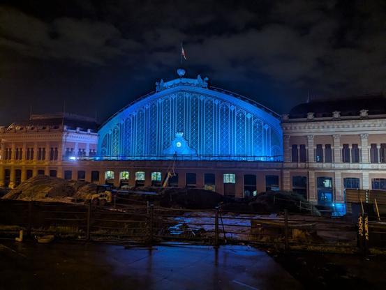 The old Madrid Atocha train hall at night. The building is lit in blue.