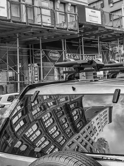 City buildings reflected on a rear window of a jeep.
