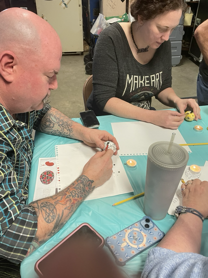 A man and a woman writing pysanky eggs with kitskas candles and instructions.