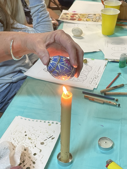 A woman with an egg over a candle with some kitskas and instructions