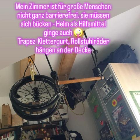 Text: Mein Zimmer ist für große Menschen nicht ganz barrierefrei sie müssen sich bücken - Helm als Hilfsmittel ginge auch- smiley - Trapez, Rollstuhlräder, Klettergurt hängen an der Decke. Und Bild der hängenden Gegenständen