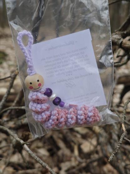 Huh?! I found something: A small plastic bag (I first thought it was trash) with a crocheted white and pink "worm" in it, with a head made from a wooden bead. It has a friendly face. 🙂