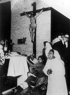 Photo that appeared in El País on 7 November 2009 with the information that the state of El Salvador recognized its responsibility in the crime. Shows Romero’s body on the floor of a church, below a statue of Jesus, with crying nuns and others standing by his side. By http://www.elpais.com/fotografia/Oscar/Arnulfo/Romero/asesinado/disparo/pecho/elpdiaint/20091107elpepuint_6/Ies/, Fair use, https://en.wikipedia.org/w/index.php?curid=24996519