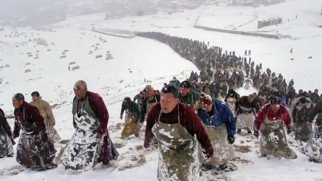 Une procession de bouddhistes montant une pente pleine de neige.