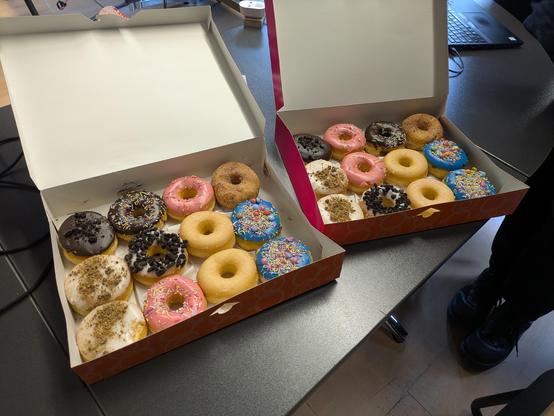 Zwei große Kartons mit wild dekorierten Donuts