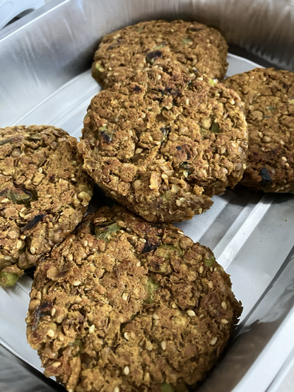 5 dark golden patties made from lentils, green onions, chopped asparagus, sesame seeds cooling in a foil tray