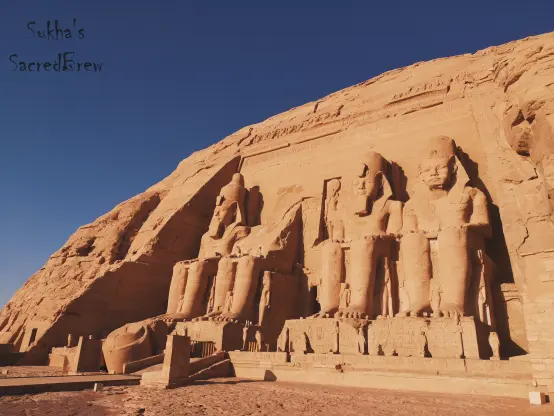 Abu Simbel in its full glory, bathed in golden sunlight that enhances the warm brown tones of the ancient stone structure.
