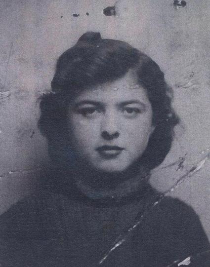 A portrait ID photo of a teenage girl. Blured foggy image. She is wearing a turtleneck sweater. She has long hair and a twisted curl at the top of her head. The head is in the central position of the frame. She is looking directly into the camera.