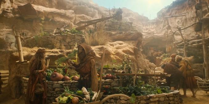 A painting of a scene from Rings of Power showing small people living in an arid cliff and valley town with water chutes and small farms.
