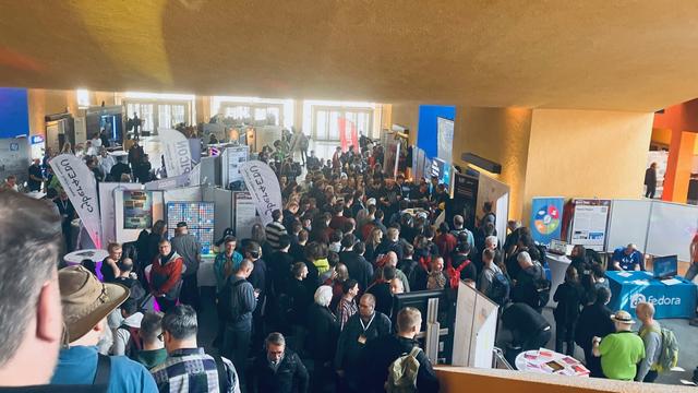 Foto: Bild in den Ausstellerbereich mit Ständen und vielen Menschen, die sich informieren.