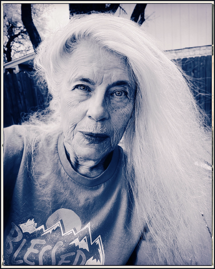 A white haired lady looks directly at the viewer. Photo is bluish black & white.