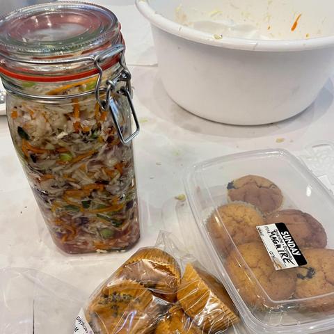 A jar of sauerkraut and muffins in a see through  bag and box