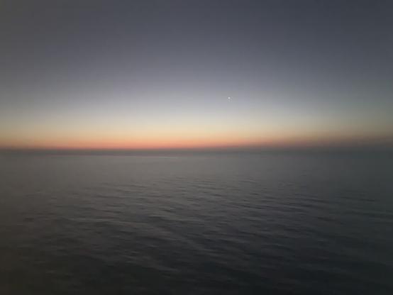 Sunset over the strait of Florida 
Deep grays on the water and sky, a thin red line on the horizon with a shrinking light behind reflecting on the waters