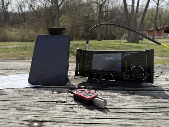 My setup on a picnic table. iPad, thermos of tea, Icom IC-705 and Modern Morse paddles. The covered bridge is in the background.