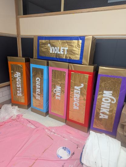 Giant oversized light boxes for golden ticket winners.

Top to bottom
Blue box name Violet
Orange box, Augustus, 
Blue charlie
Pink Mike
Red veruca
Purple wonka