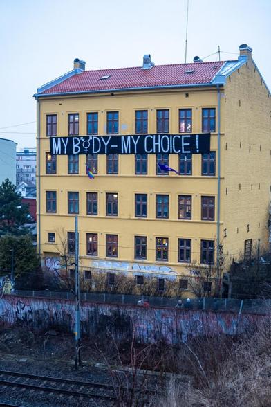 Four story yellow building with a banner reading "My body - my choice!"