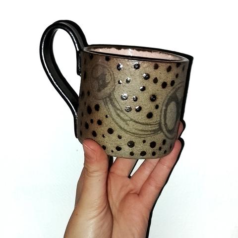 Ceramic grey stoneware mug with piercing design done in underglaze pencil with dots in metallic glaze and a pink inside. Done by artist Christine Lykkeh