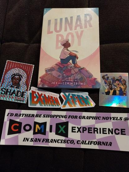 Stickers with classic Storm with the text "Shade came from reading", the Lunar Boy graphic novel, the cast of 90s X-Men in the style of Paris is Burning with the text "Genosha is burning", two stickers in the X-Men font reading "The hard-femme Ex-Men" and "The soft-butch X-Fem", and a bumper sticker that reads "I'd rather be shopping for graphic novels at Comix Experience in San Francisco, California"Stickers with classic Storm with the text "Shade came from reading", the Lunar Boy graphic novel, the cast of 90s X-Men in the style of Paris is Burning with the text "Genosha is burning", two stickers in the X-Men font reading "The hard-femme Ex-Men" and "The soft-butch X-Fem", and a bumper sticker that reads "I'd rather be shopping for graphic novels at Comix Experience in San Francisco, California"