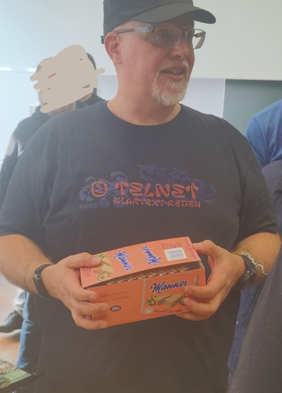 Der Leyrer im "Telnet - Klartext Reden!" T-Shirt mit Mannerschnitten in der Hand.