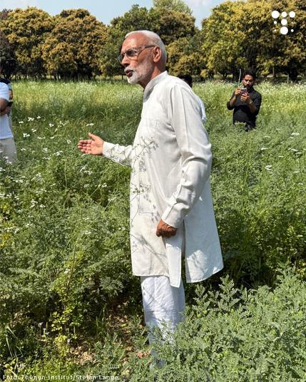 Rohitashwa Gakhar, Director Operations beim International Competence Centre for Organic Agriculture (ICCOA), auf einem grünen Feld, erklärt etwas.
