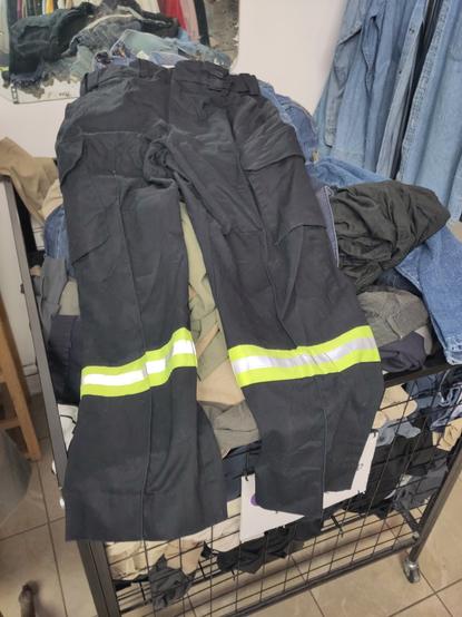 blue uniform pants with a bright yellow reflective strip across the legs on a bin of pants