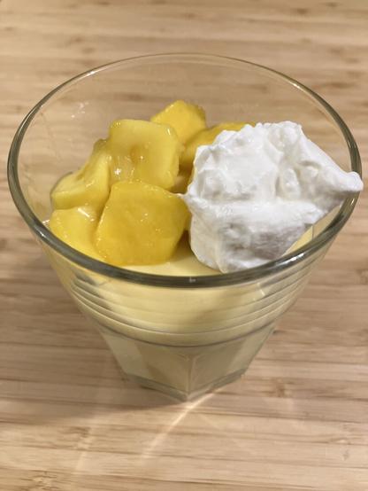 A light orange pudding topped with fresh mango and whipped cream.