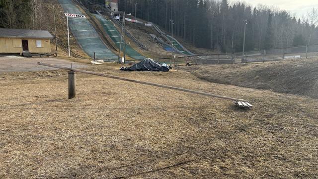 Napakelkka lumettomalla nurmella mäkihyppypaikan vieressä