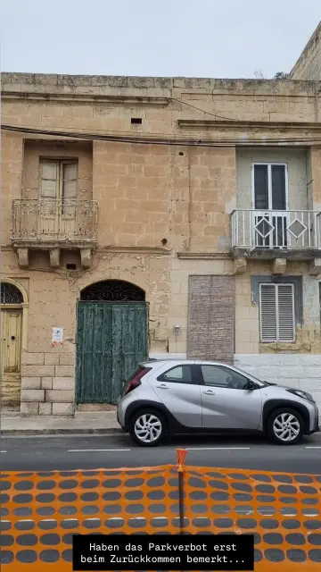 Das Auto steht vor einem Haus, an dem ein "Parken verboten"-Zettel hängt