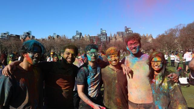Group of friends posing after playing Holi, covered in bright colours.