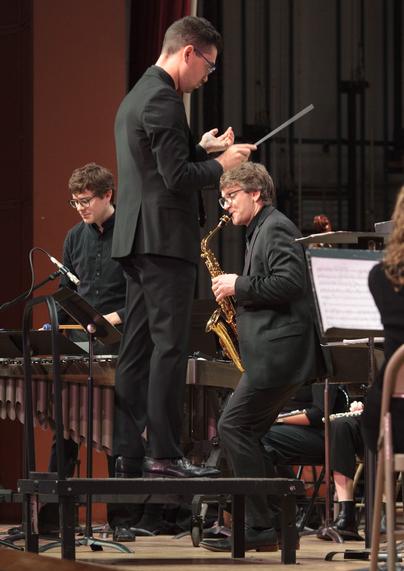 Left to right: Nigel Ferandez on vibraphone, David Blumenthal standing on the maestro's podium, Nick Natalie plays the saxophone.