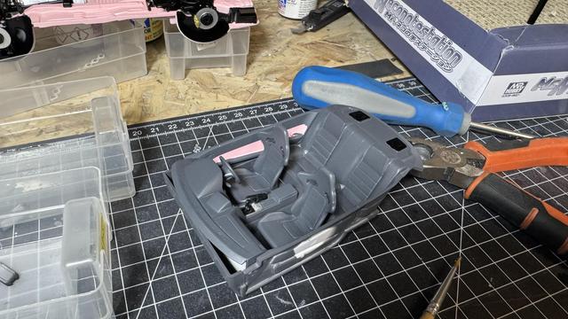 Cockpit of a Nissan Skyline GT-R (34) by Tamiya in pink on top of a workbench.