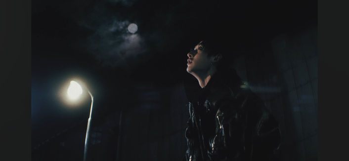 Bang Chan at night with a streetlight and a blue full moon behind him