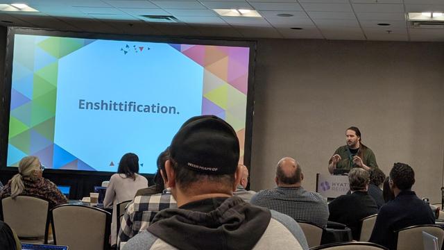 Time Hestenet of the Drupal Association talking about the slide projected which reads, "Enshittification."
