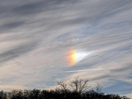 A bright whisp of rainbow amongst white and gray my horse tail clouds