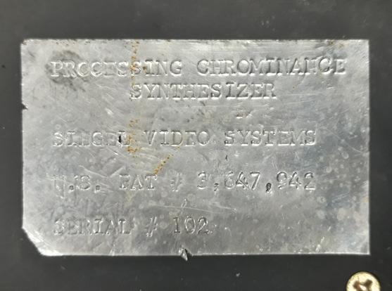 A shiny - and obviously ancient- sticker on the back of a piece of electronic equipment, saying "Processing Chrominance Synthesizer, Siegel Video Systems".