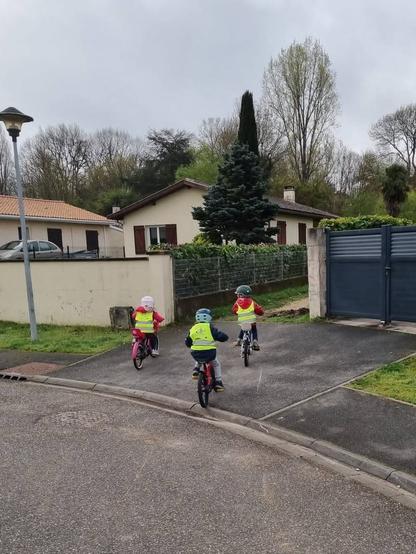 Trois enfants de 4 à 5 ans sur leur vélo respectif en chemin pour l'école maternelle de Tresses.
Ils sont dans une zone résidentielle.