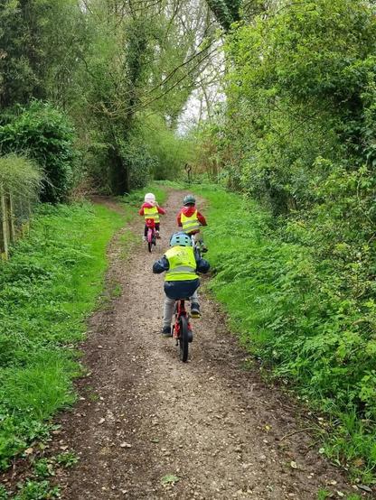 Trois enfants de 4 à 5 ans sur leur vélo respectif en chemin pour l'école maternelle de Tresses.
Ils sont dans un chemin en sous-bois.