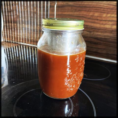 A cold brew jar with already coffee brown water sitting on a stove top