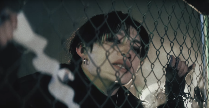 Another shot of Bang Chan behind a chain link fence because this is perfect for him