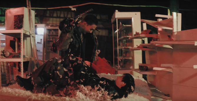 In an abandoned store, on top of a wrecked mattress, Bang Chan lies on his back with his knees bent up. Hyunjin is straddling Chan's waist. They're both looking at each other with delighted and somewhat crazed expressions. There are feathers everywhere, like a pillow got destroyed