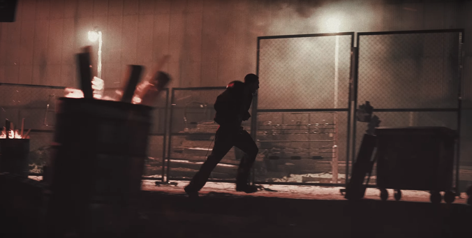 Silhouette of Hyunjin running through an abandoned area. The lighting is red-tinged.