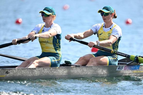 Two women in Australian sports uniforms rowing.