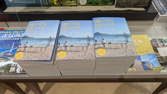 A stack of Setouchi Triennale 2025 guidebooks on a table in a bookstore in Japan.