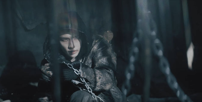 Chained sad Hyunjin looking up, seeming to sense that something is happening