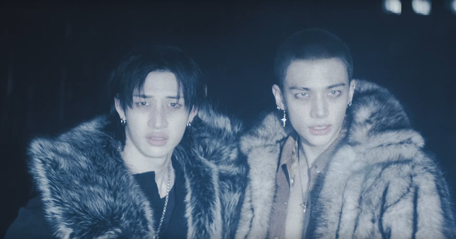 Two reunited boys in furry coats that are somewhat reminiscent of wolf pelts. Both look worried and scared. Hyunjin also looks determined and desperate.