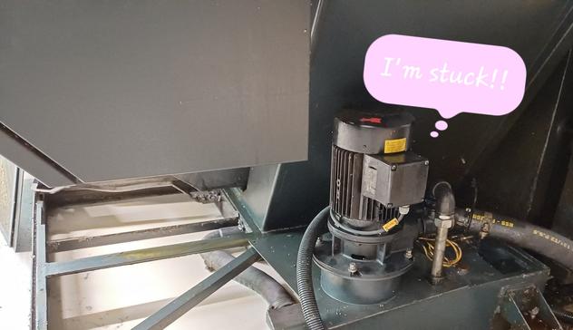 A photo of a black collection tray with a transfer pump on top, from which a hose extends. Inside the tray is a whitish emulsion. The pump has a pink thought bubble, thinking, "I'm stuck!"