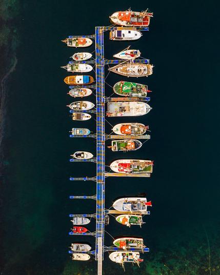 Brightly coloured fishing boats moored at a dock in an emerald green sea.
