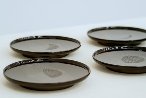 At a low angle, it reveals a white and black inverse of the phases of the moon on each plate