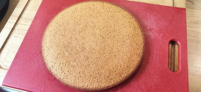 Un financier, le gâteau, tout rond posé sur une planche à découper rouge.